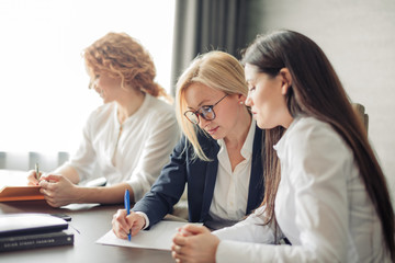business, teamwork and women concept - female team of young caucasian women entrepreneurs working with laptop computer