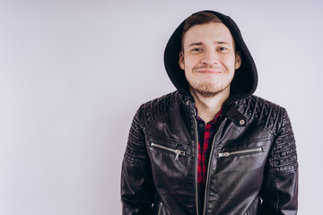 Obraz premium Man in trendy jacket on white background. Portrait of young male in leather jacket zipping up and smiling at camera on white background