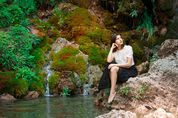 Fototapeta premium Beautiful dark haired girl posing in river with green plants. Beauty, fashion. Spa, healthcare. Tropical vacation. Natural pool.