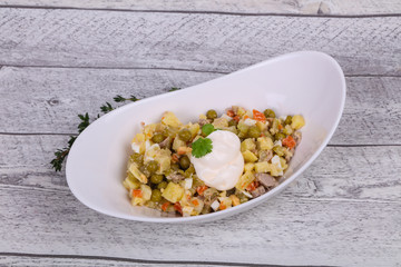 Traditional Russian salad with chicken in the white bowl