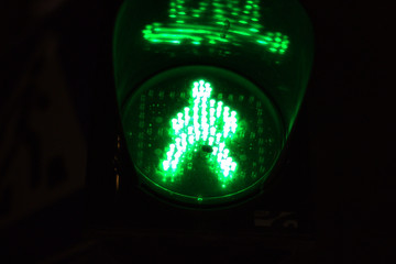 Green light of traffic light on the pedestrian crossing in the form of a human silhouette. Road...