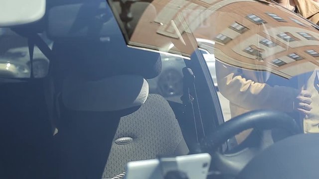 A man gets into the car and turns on the navigator on the smartphone