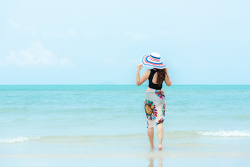 Summer Holiday. Lifestyle woman chill holding big white hat and wearing bikini fashion summer trips walking on the sandy ocean beach. Happy woman enjoy and relax vacation. Lifestyle Travel 