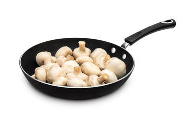 Frying pan with whole raw champignons isolated on white.