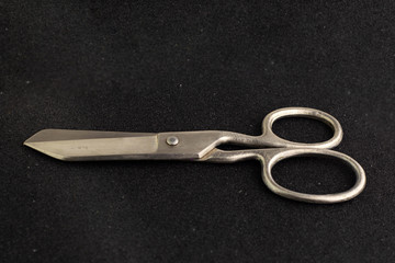 vintage big seamstress scissors isolated on black background. short focus