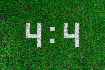 Football score 4:4.White numbers four and four are drawn on the green grass,creative scoreboard