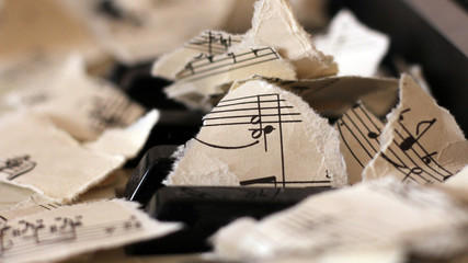 Torn musical notes, pieces of paper on piano