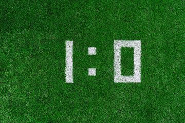 Football score 1:0.White numbers one and zero are drawn on the green grass