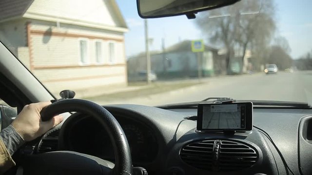 A man gets into the car and turns on the navigator on the smartphone