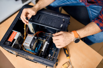 professional IT specialist repairing a PC, top view cropped photo.