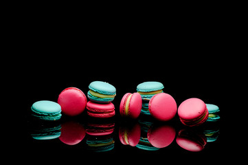 diffrent colorfull macarons on black background .pink color and ment color macaroons