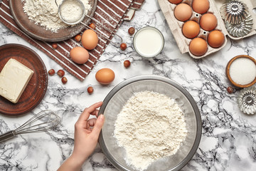 Close-up shot. Top view of a baker cook place, hands are working with a raw dough on the marble table background.