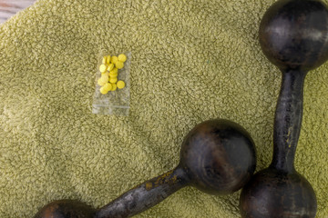 dope and bodybuilding: pills next to 2 black metal dumbbell, short focus