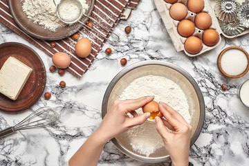Close-up shot. Top view of a baker cook place, hands are working with a raw dough on the marble table background.