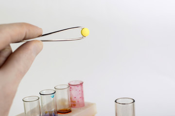 invention of synthetic narcotic drugs: a person holds a sample of a new drug above the table with other samples, short focus