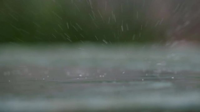 The rain falls on a glass plate and the water splashes and bubbles in slow motion with 180p