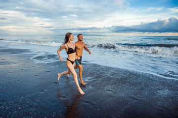 Fototapeta premium Girl and man on the beach running.