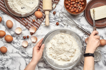 Close-up shot. Top view of a baker cook place, hands are working with a raw dough on the marble table background.
