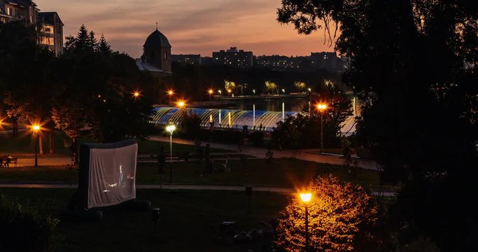 People watch the night theater in the park, near the lake, at sunset, timelapse