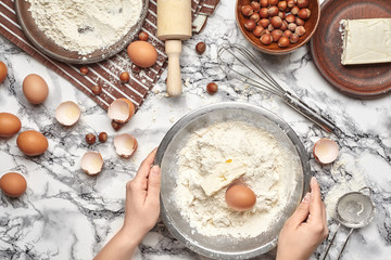 Close-up shot. Top view of a baker cook place, hands are working with a raw dough on the marble table background.