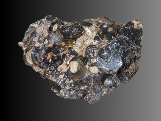 Black meteorite on dark background.  Colorful glittering compound stone. It looks like a piece of space.