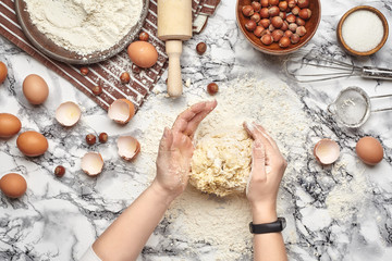 Close-up shot. Top view of a baker cook place, hands are working with a raw dough on the marble table background.