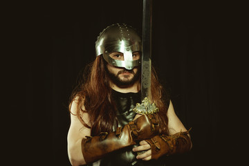 Viking warrior with metallic helmet and animal skins. leather gauntlets, red wooden shield with...