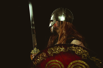 Knight, Viking warrior with metallic helmet and animal skins. leather gauntlets, red wooden shield...