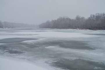 Winter day. River frozen - covered with ice and naked trees covered with white snow on there branches. Walking on nature