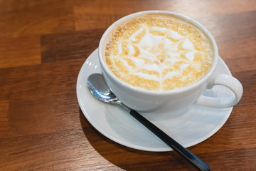 Coffee cup with star shape art foam on wood table background on table top at cafe.