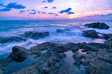 Long exposure image of Dramatic sky and wave seascape with rock in sunset scenery background