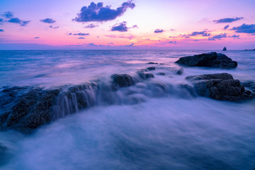 Long exposure image of Dramatic sky and wave seascape with rock in sunset scenery background