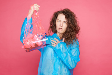 Emotional curly haired frustrated female volunteer with ugly grimace grabs wastes, wants to stop...
