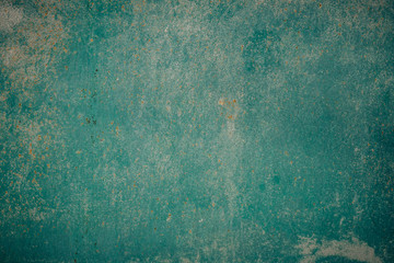 Old grunge weathered crumbled peeling green painted plastered house wall surface detail close up as background
