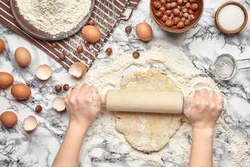 Close-up shot. Top view of a baker cook place, hands are working with a raw dough on the marble...