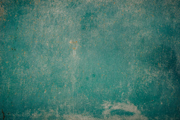 Old grunge weathered crumbled peeling green painted plastered house wall surface detail close up as background