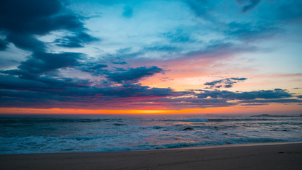 Fototapeta na wymiar Vivid red sky at sunset on the beach with dark clouds