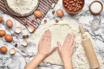 Close-up shot. Top view of a baker cook place, hands are working with a raw dough on the marble...