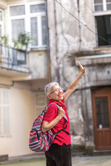 Senior old woman tourist with a backpack preparing to leave her home to go travelling