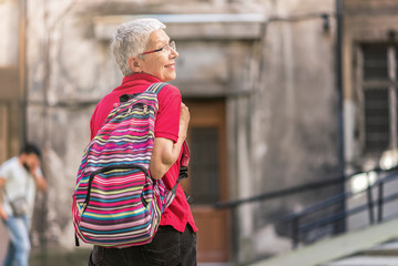 Senior old woman tourist with a backpack preparing to leave her home to go travelling