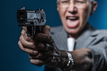 An underground agent, angry and frustrated senior woman aiming a gun about to fire