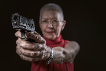 Classy undercover agent, a senior old woman aiming a gun, policewoman or a secret agent