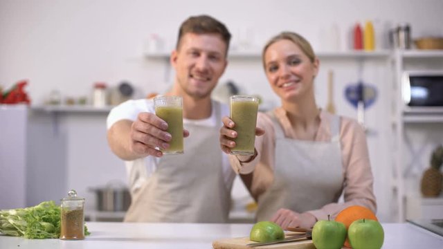 Joyful couple holding spirulina smoothie, recommending healthy drink, vitamins