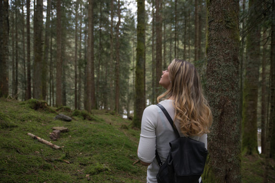 Girl walking in the green forest and listening to the nature around her