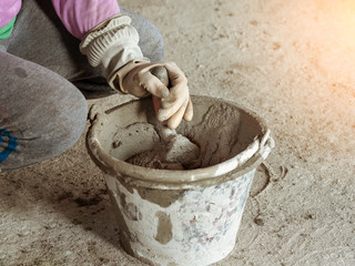hand with trowel and bucket with mortar at consturction site