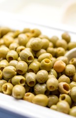 Close up of fresh and organic pitted green olives on a luxury Greek buffet with a serving spoon