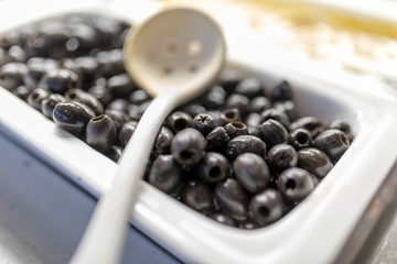 Close up of fresh and organic pitted black olives on a luxury Greek buffet with a serving spoon