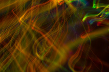 Fototapeta premium Blurred neon lights in motion. Thin curved multicolor lines on dark background. Lens flare effect.