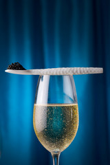 porcelain fork with caviar and champagne, with blue background