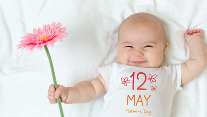 Mother's Day message with baby girl holding a flower